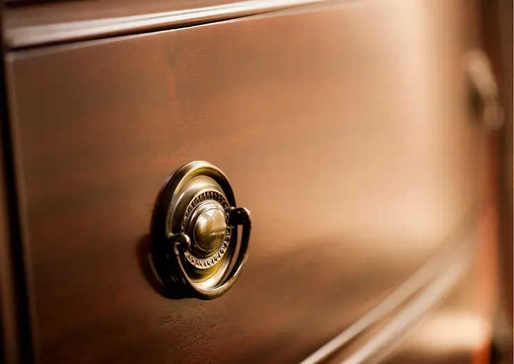 A close up of a wooden drawer with a brass handle.