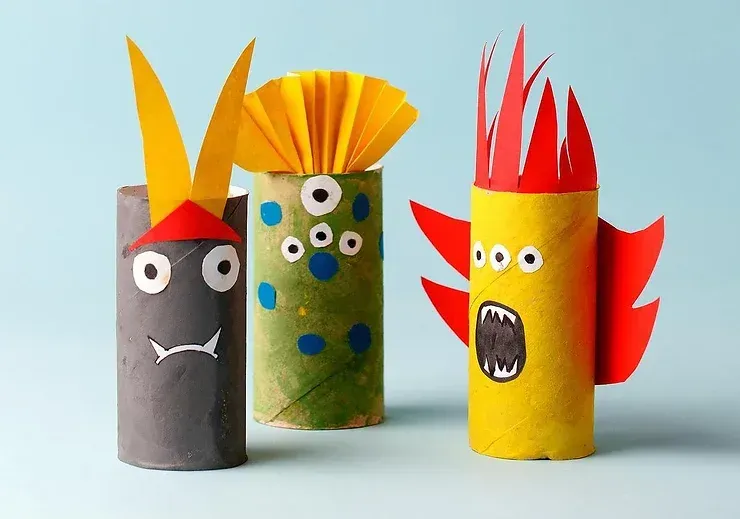 Three toilet paper rolls are decorated to look like monsters.