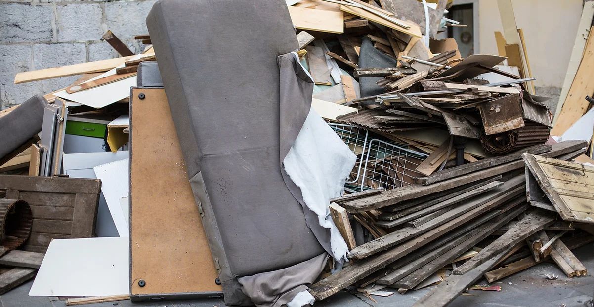 Pile of construction debris and discarded furniture in an outdoor setting.