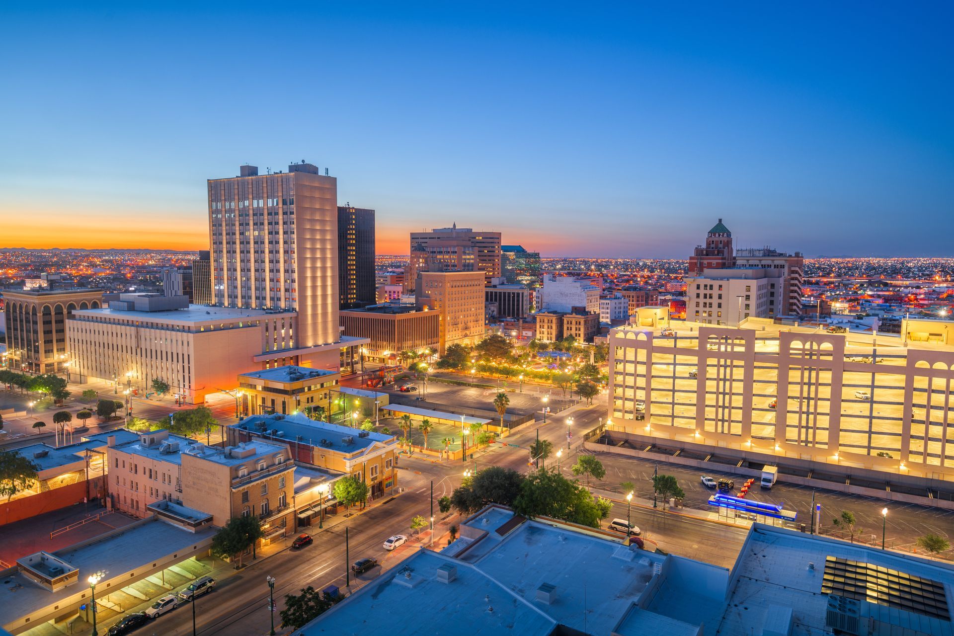 Downtown San Antonio skyline at dusk with lit buildings and clear blue sky.