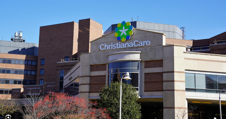 ChristianaCare hospital exterior with sign, brick buildings, and a blue sky.