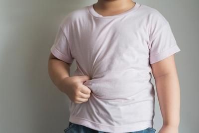 Child in pink shirt pinching belly.