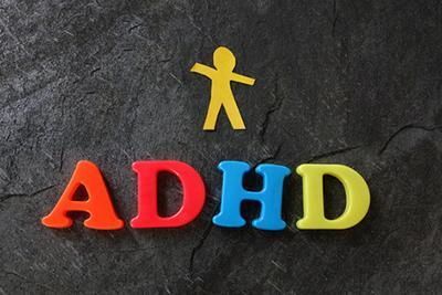 Colorful ADHD letters with a cutout figure on a dark textured surface.