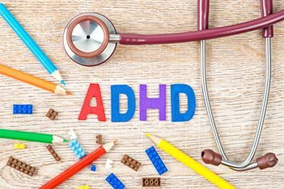 ADHD spelled out with colorful letters, stethoscope, pencils, and building blocks on wood surface.