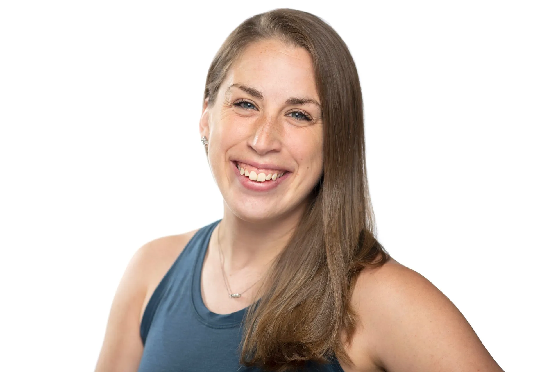 Woman smiles, looking at the viewer. Long brown hair, blue tank top, white background.