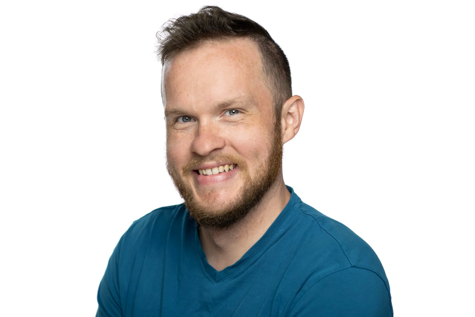 Man with a beard smiling, wearing a blue shirt.