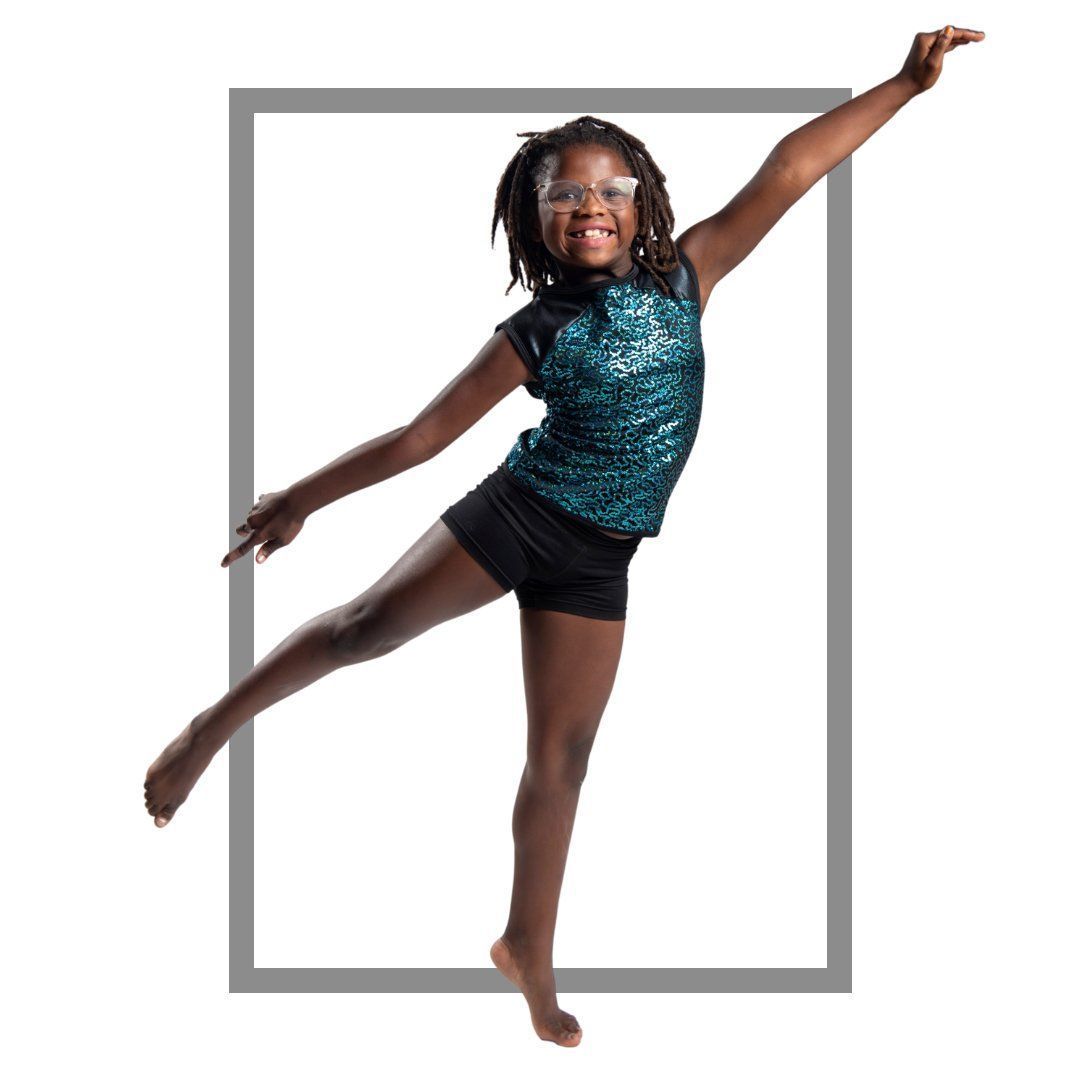 Girl in teal sequin top and black shorts dancing, framed in a gray rectangle, smiling.