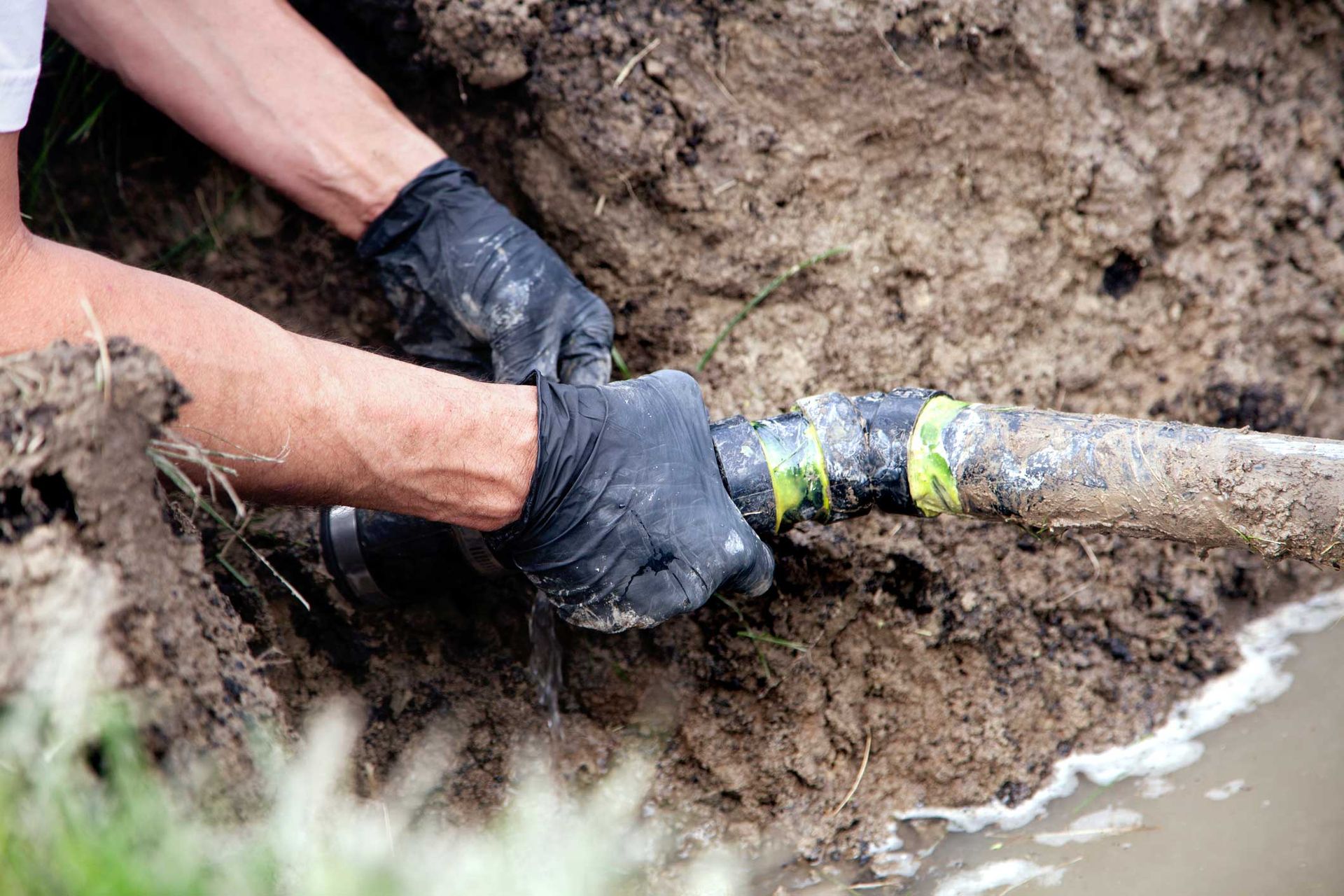 A man is fixing a pipe in the dirt.