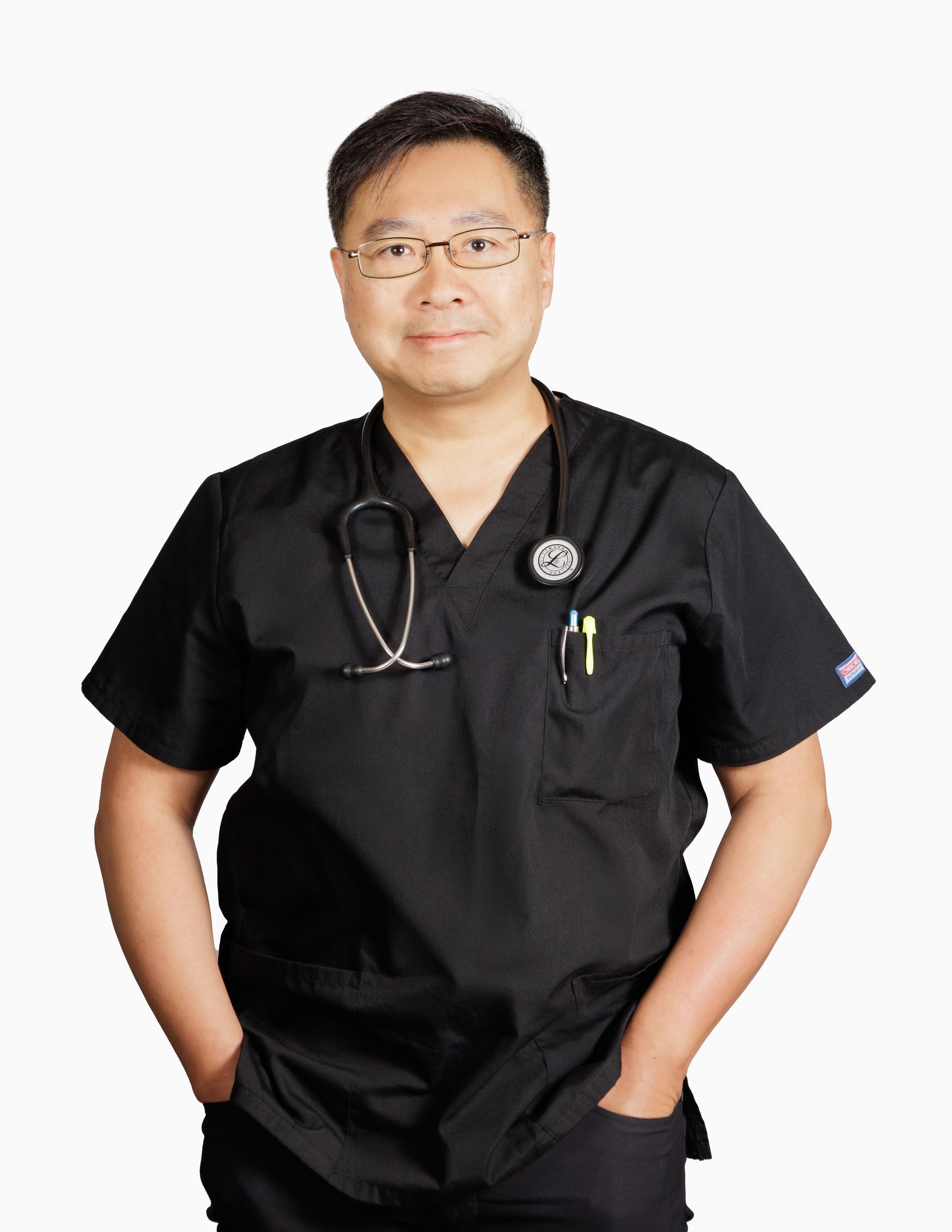 A man wearing a black scrub top with a stethoscope around his neck