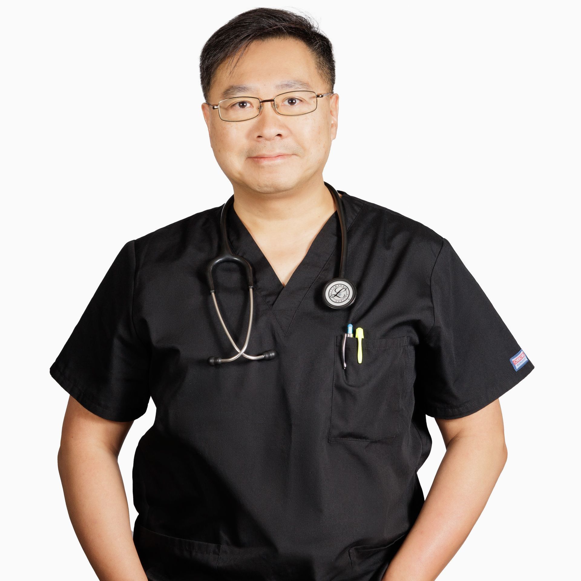 A man wearing a black scrub top with a stethoscope around his neck