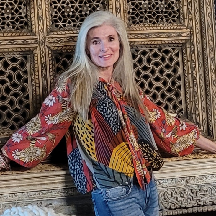 A woman in a colorful shirt is sitting on a bench