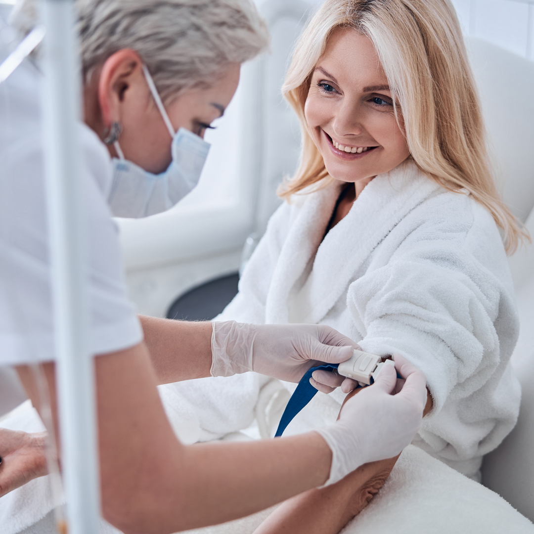 A woman in a bathrobe is getting an injection from a nurse.