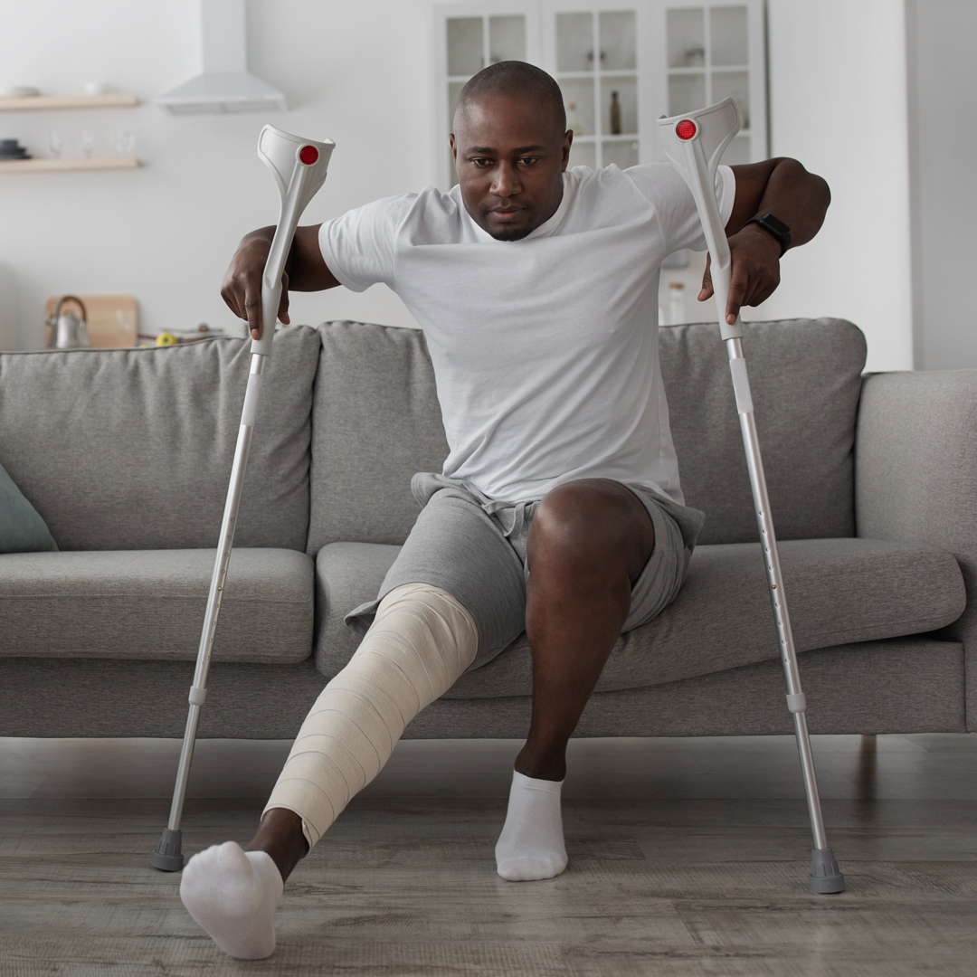 A man with crutches is sitting on a couch