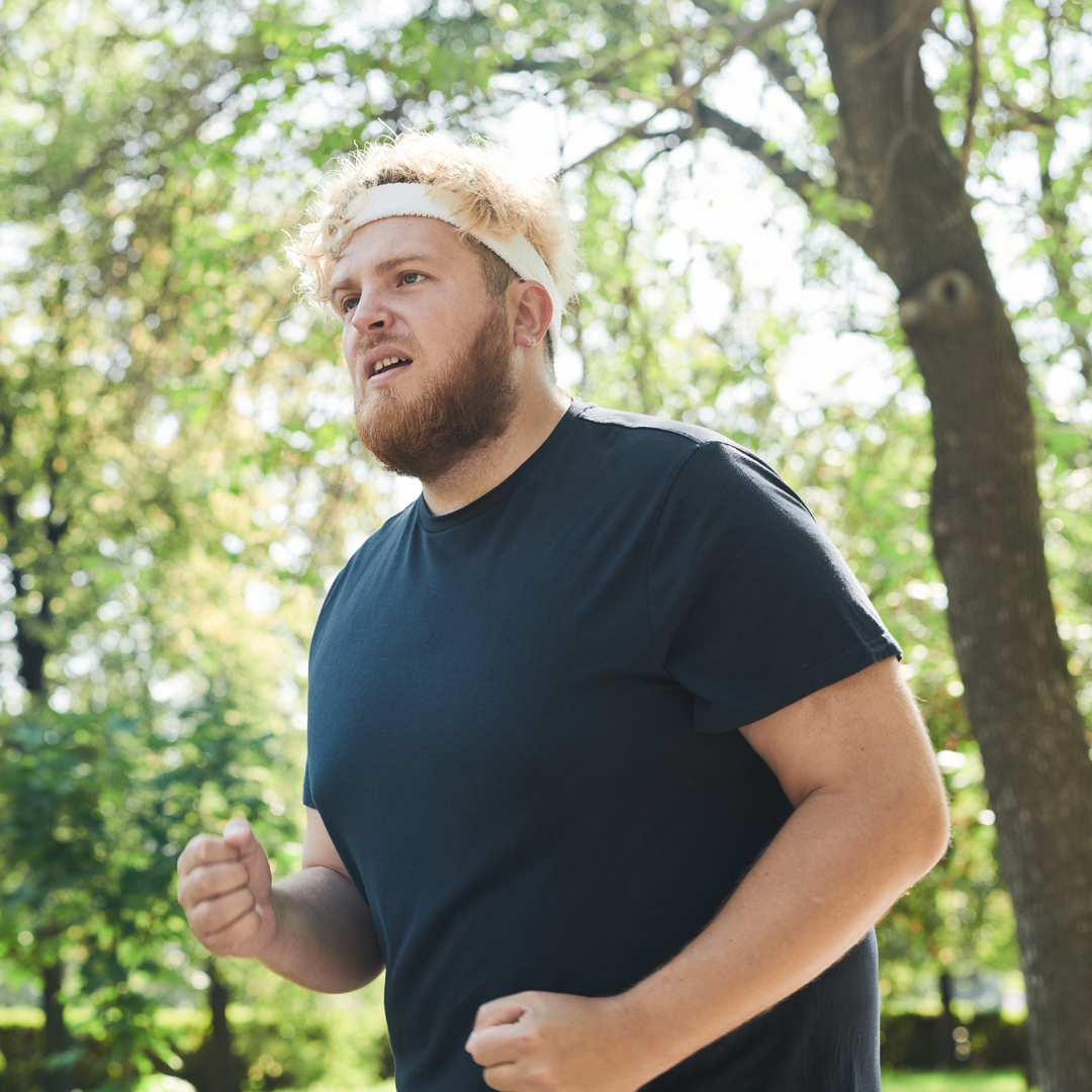 A man wearing a headband is running in a park.