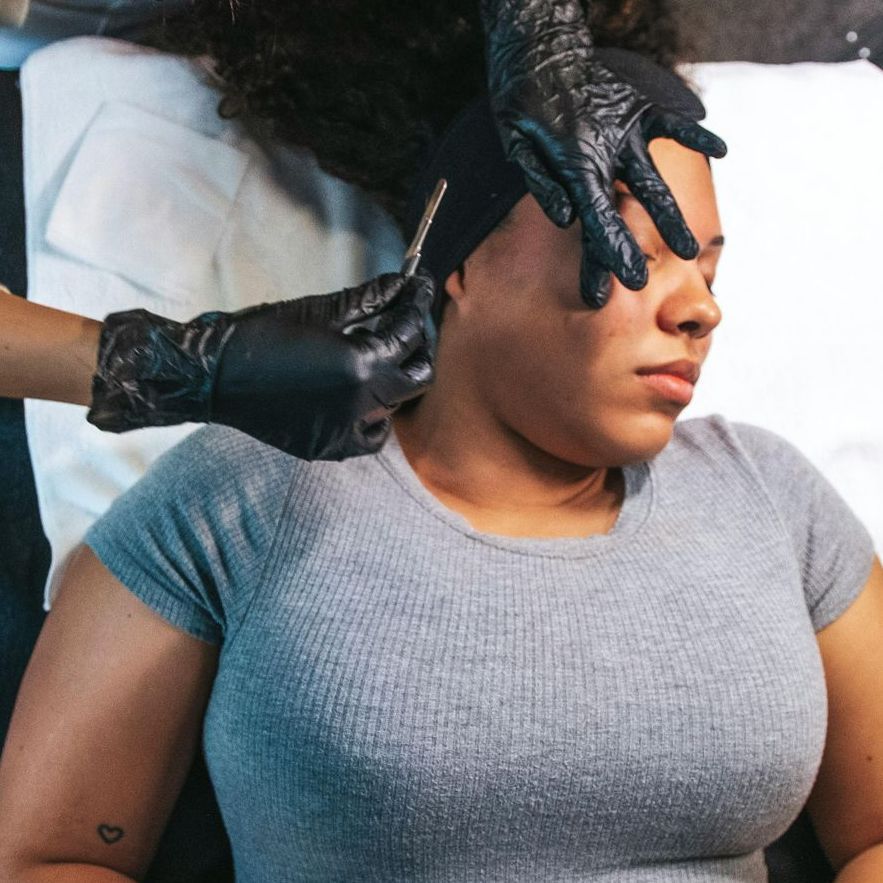 A woman with a heart tattoo on her arm is getting a facial treatment