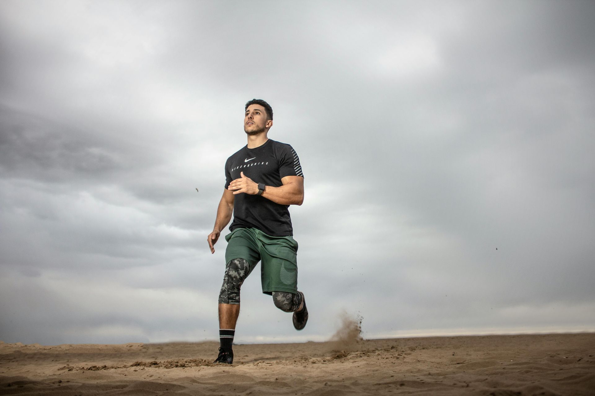A man is running in the desert on a cloudy day.