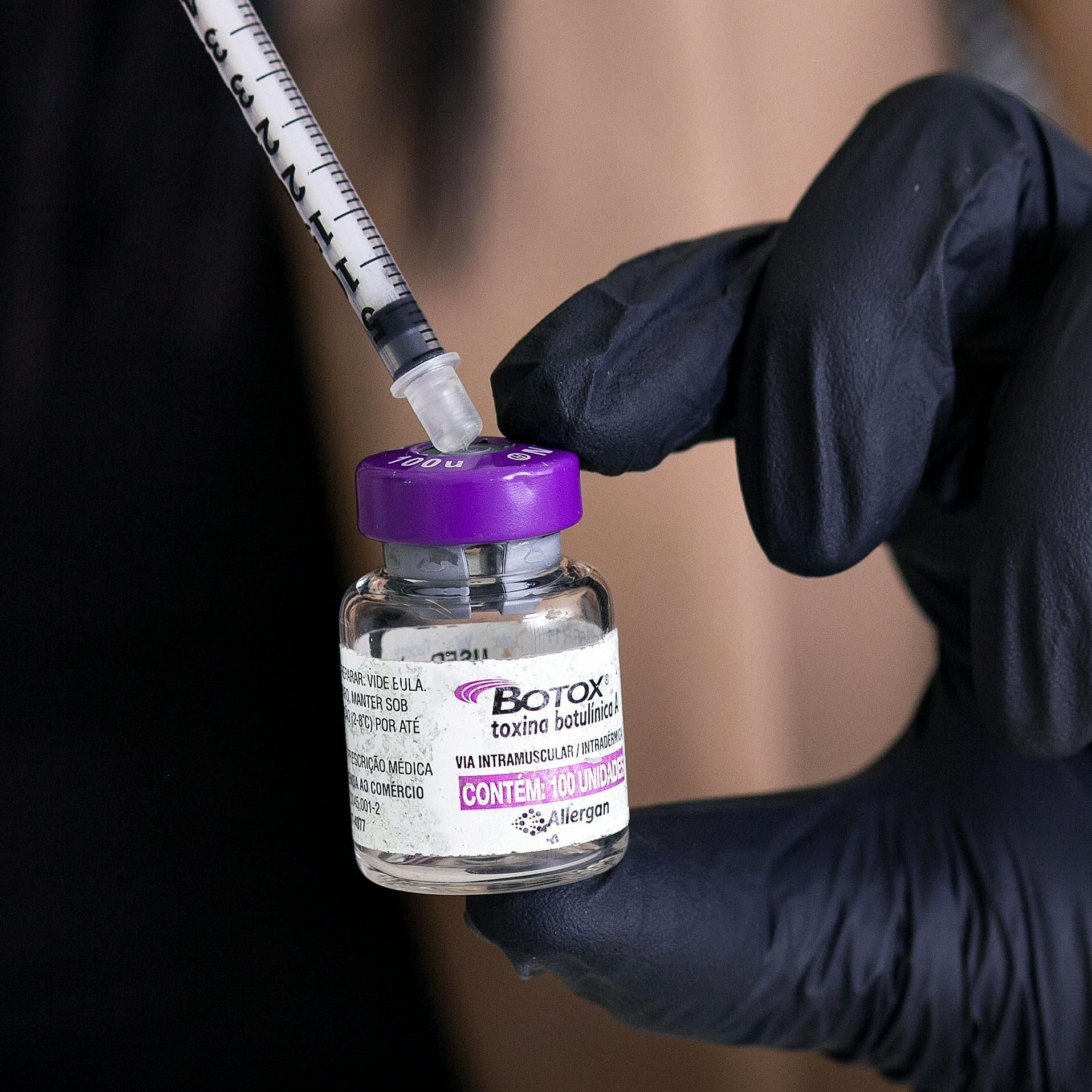 A person is holding a bottle of botox and a syringe