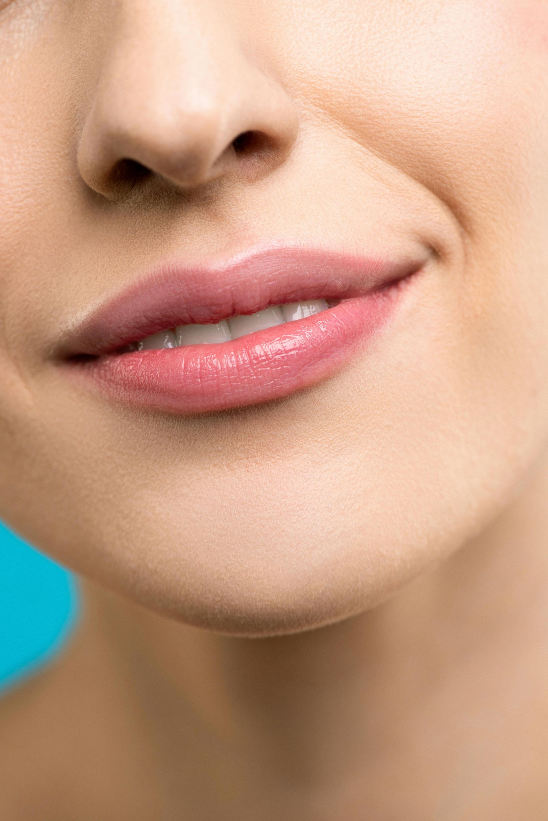 A close up of a woman 's lips with pink lipstick on a blue background.
