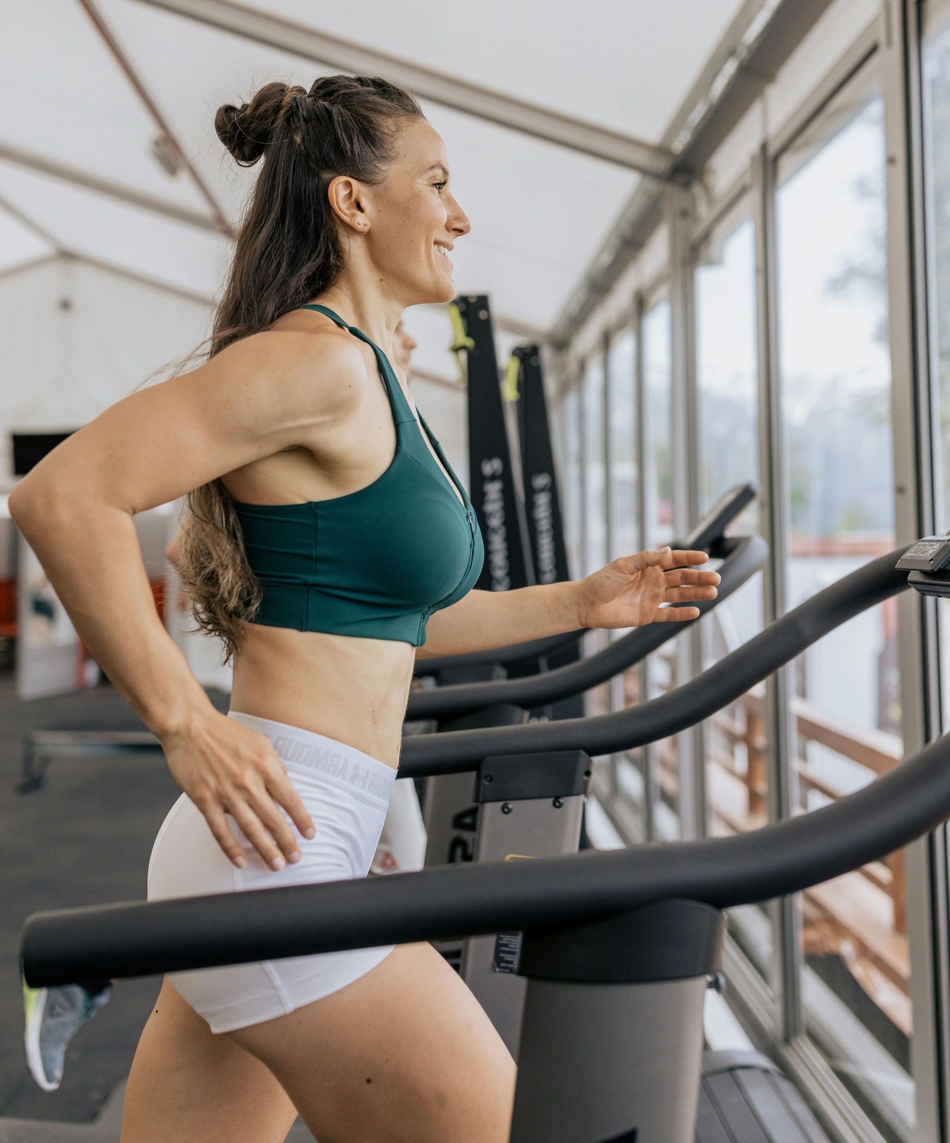 A woman is running on a treadmill in a gym.