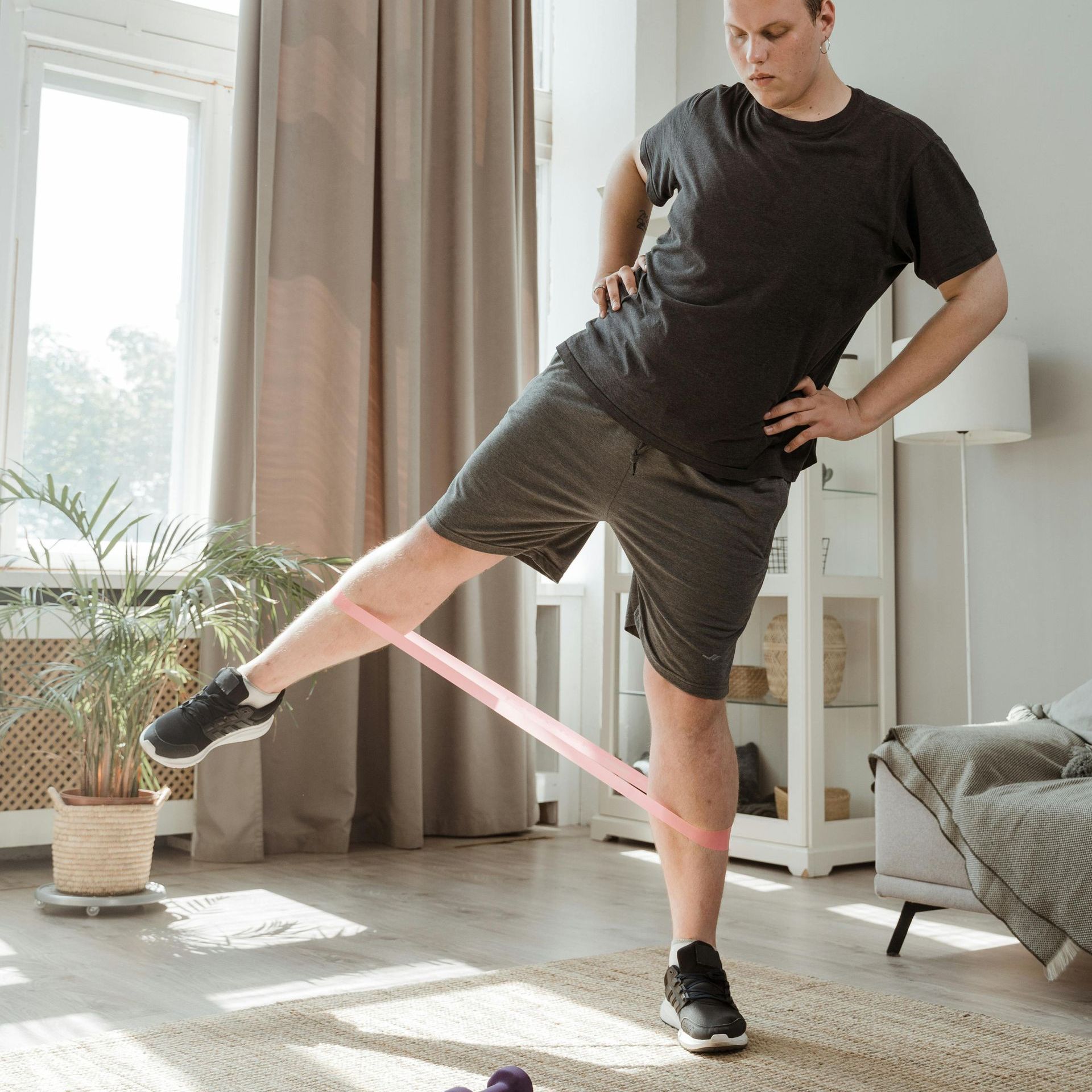 A man is doing exercises with a resistance band in a living room.