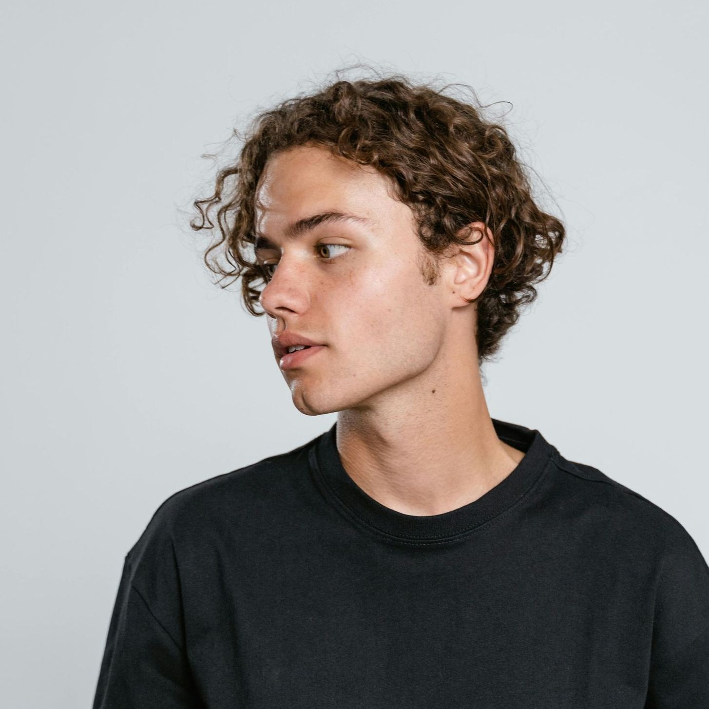A young man with curly hair is wearing a black shirt