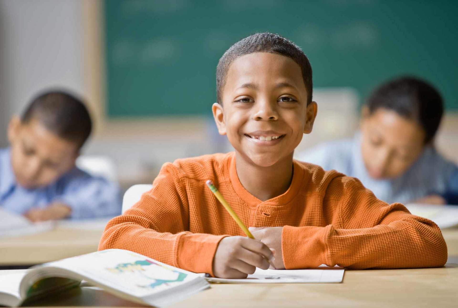 Mixed Race boy writing at school desk