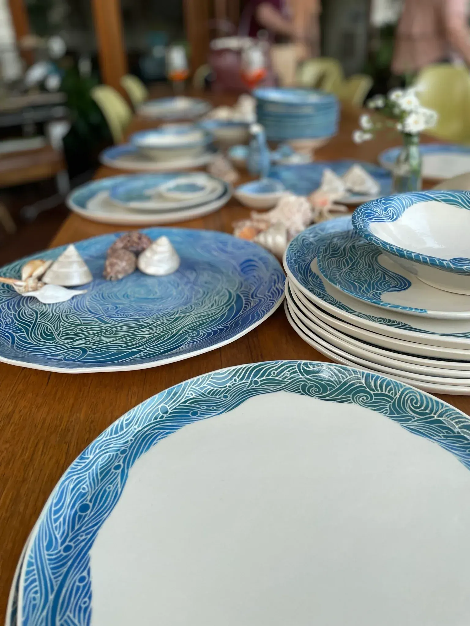 Table set with blue and white patterned dishes, seashells, ready for a meal.