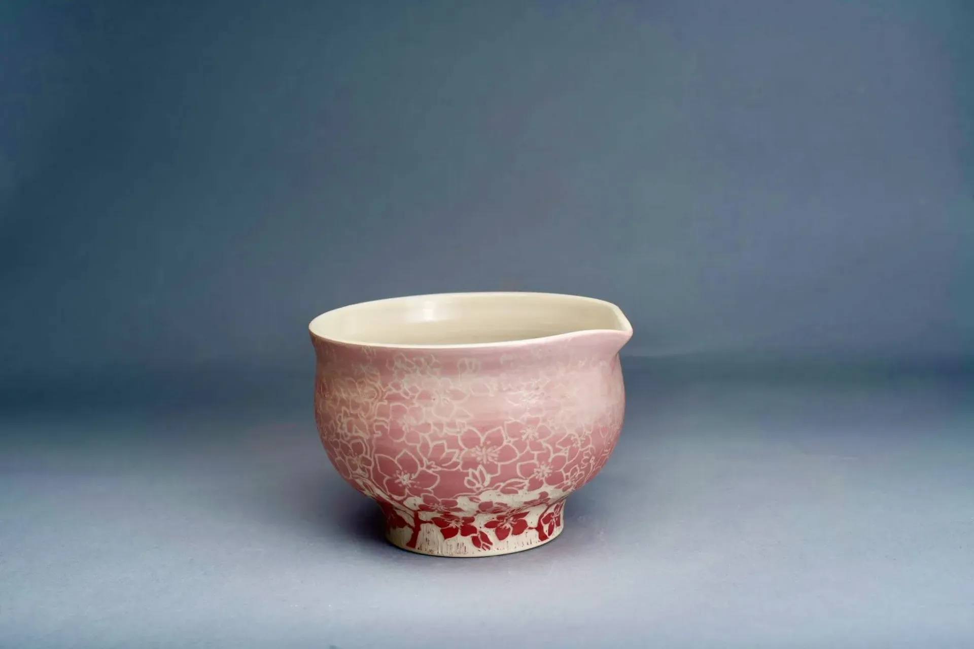 Pink and white ceramic bowl with crackle glaze, on a gray surface.