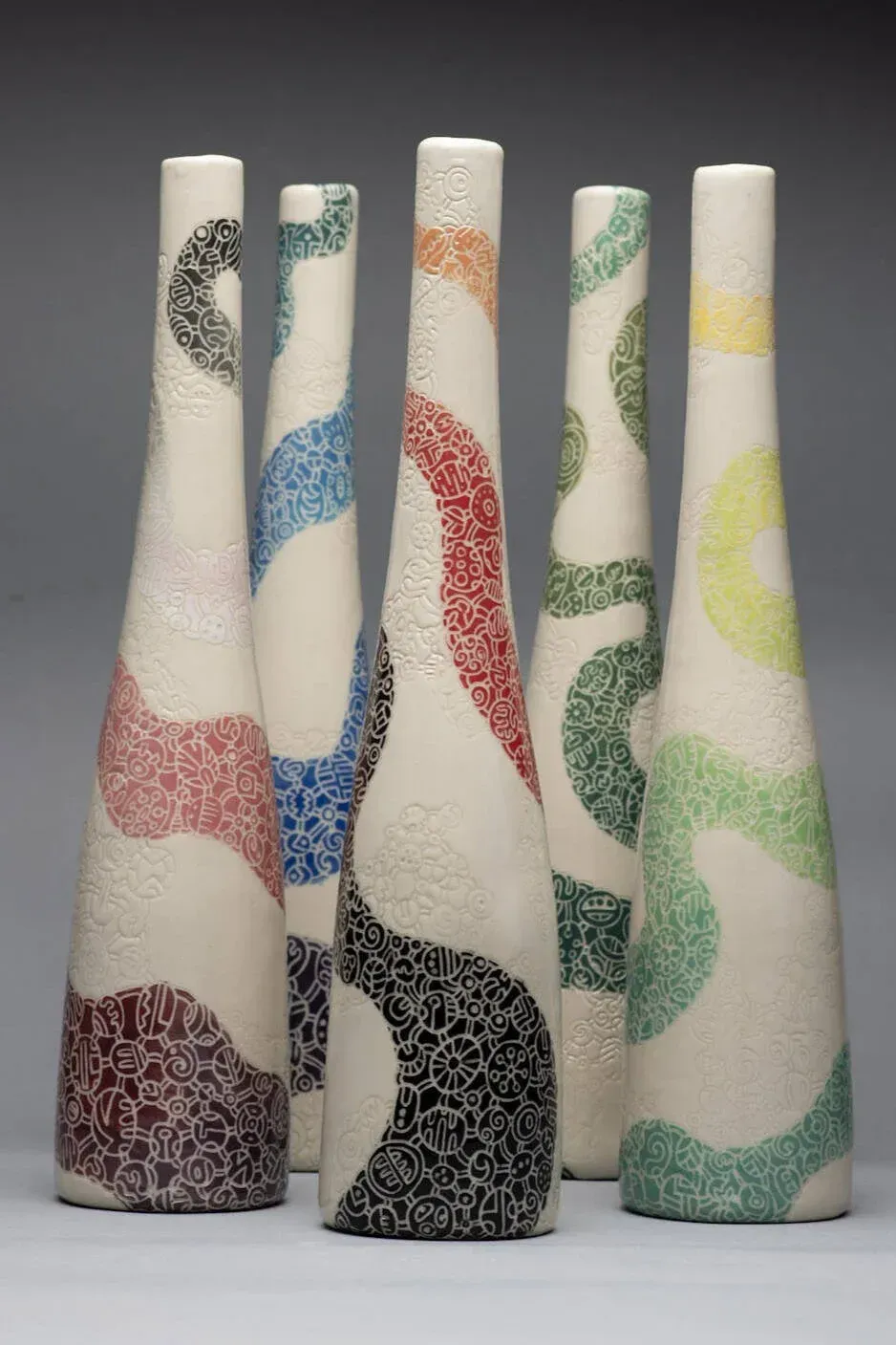 Five white ceramic vases with colorful, patterned swirls.