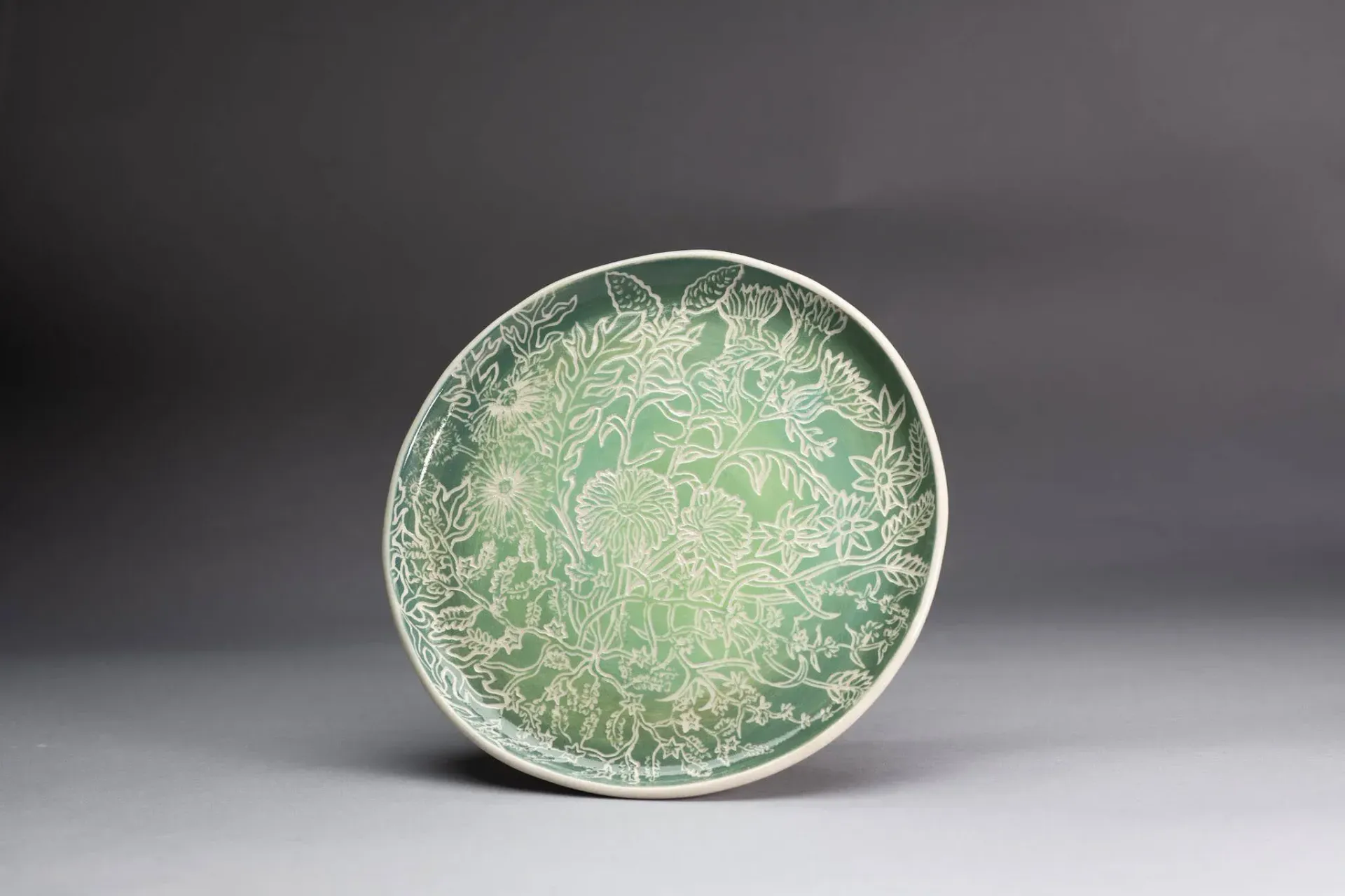 Green petri dish with white, branching microbial growth.