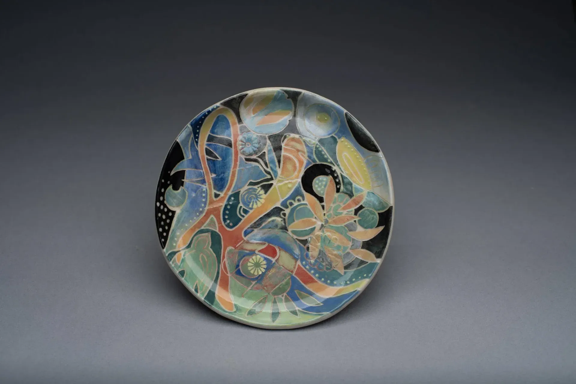 Ceramic bowl with colorful floral design, set against a dark gray background.