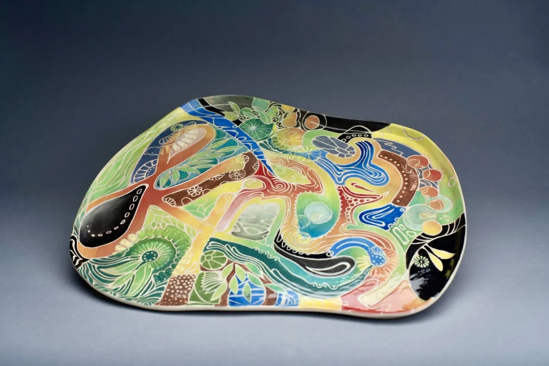 Colorful, abstract ceramic platter with swirling lines and patterns in various hues.