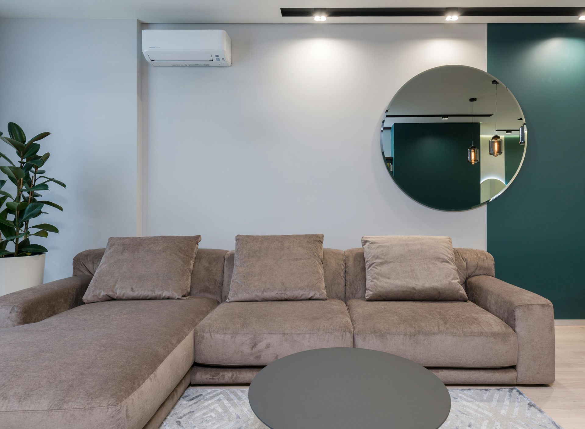 A living room with a couch and a round mirror on the wall.