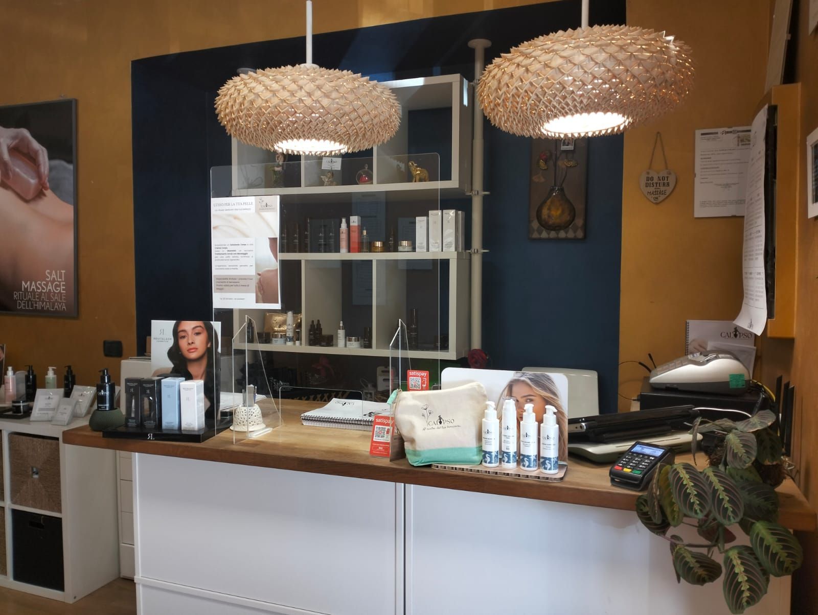 Un bancone della reception in un salone con due lampade di vimini appese al soffitto.