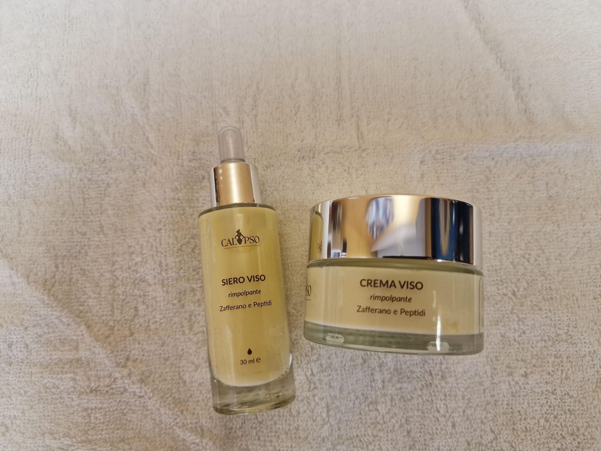 Quattro flaconi di cosmetici sono appoggiati su un asciugamano bianco.