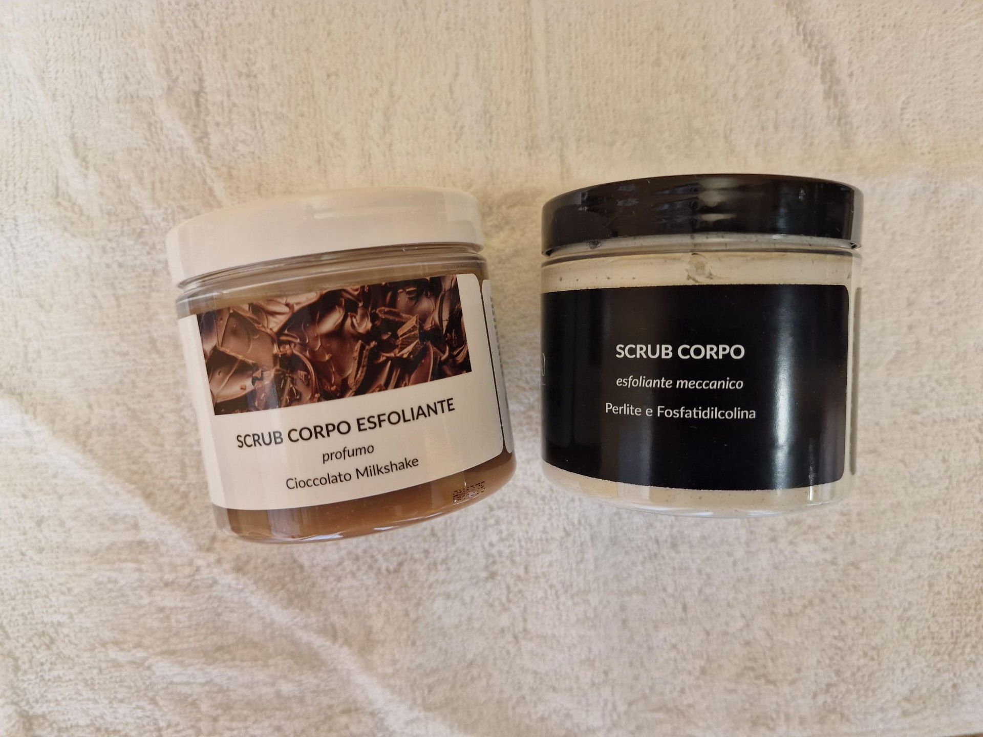 Due barattoli di cosmetici sono appoggiati su un panno bianco.