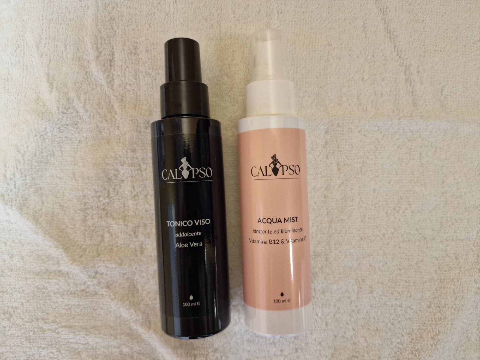 Due bottiglie di cosmetici sono appoggiate su un asciugamano bianco