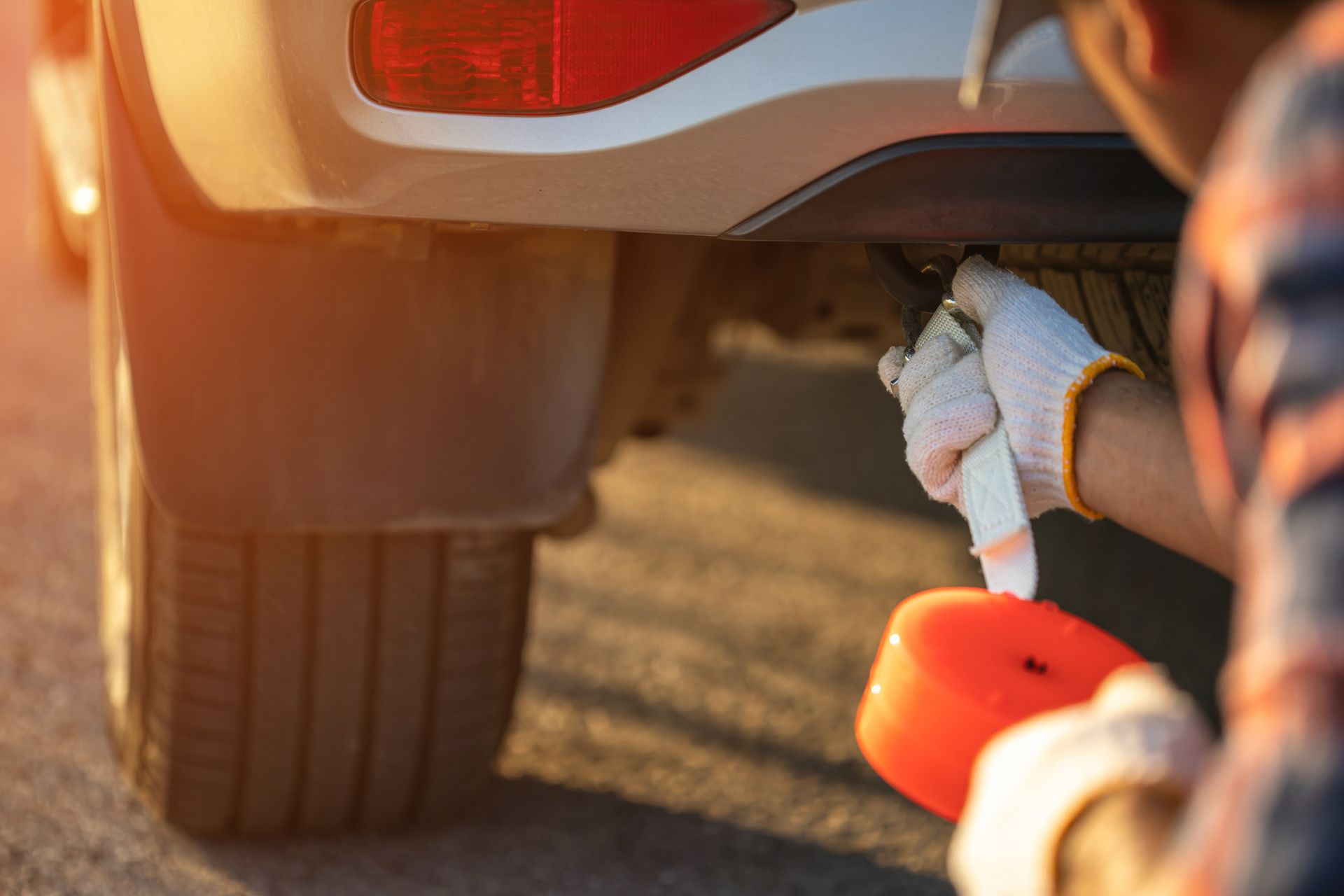 Person in gloves inspecting a vehicle's undercarriage with a sponge in hand. Person in gloves inspecting a vehicle's undercarriage with a sponge in hand.