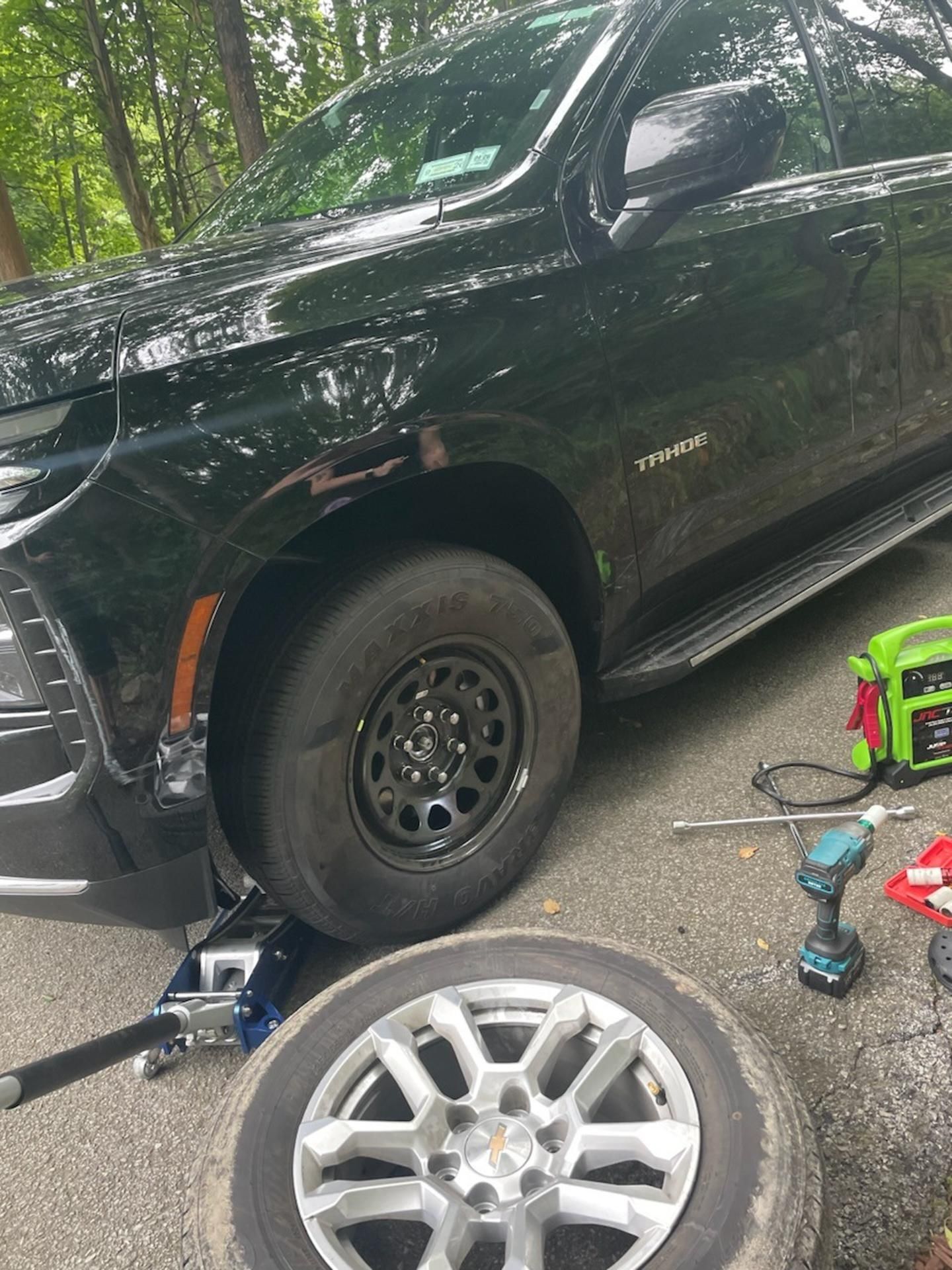 White car being loaded onto a tow truck on the side of a road.