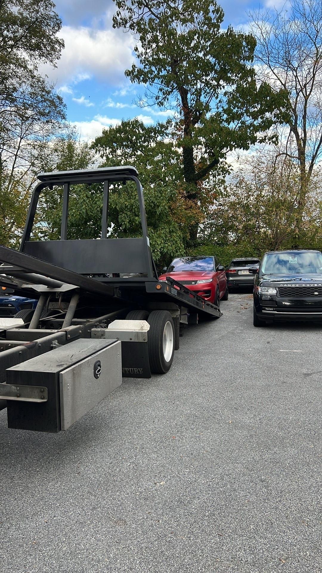 White car being loaded onto a tow truck on the side of a road.