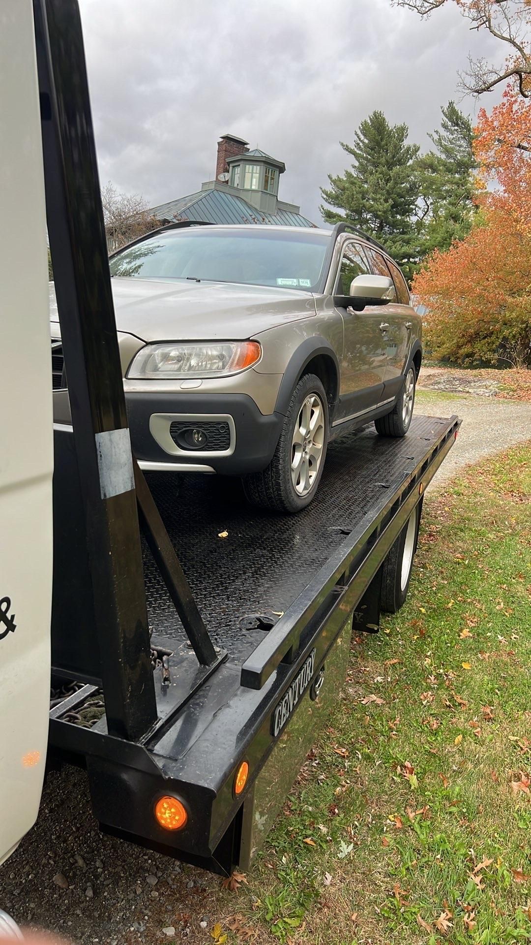 Tow truck driver smiling, wiping hands, standing near tow truck and car. Tow truck driver smiling, wiping hands, standing near tow truck and car.