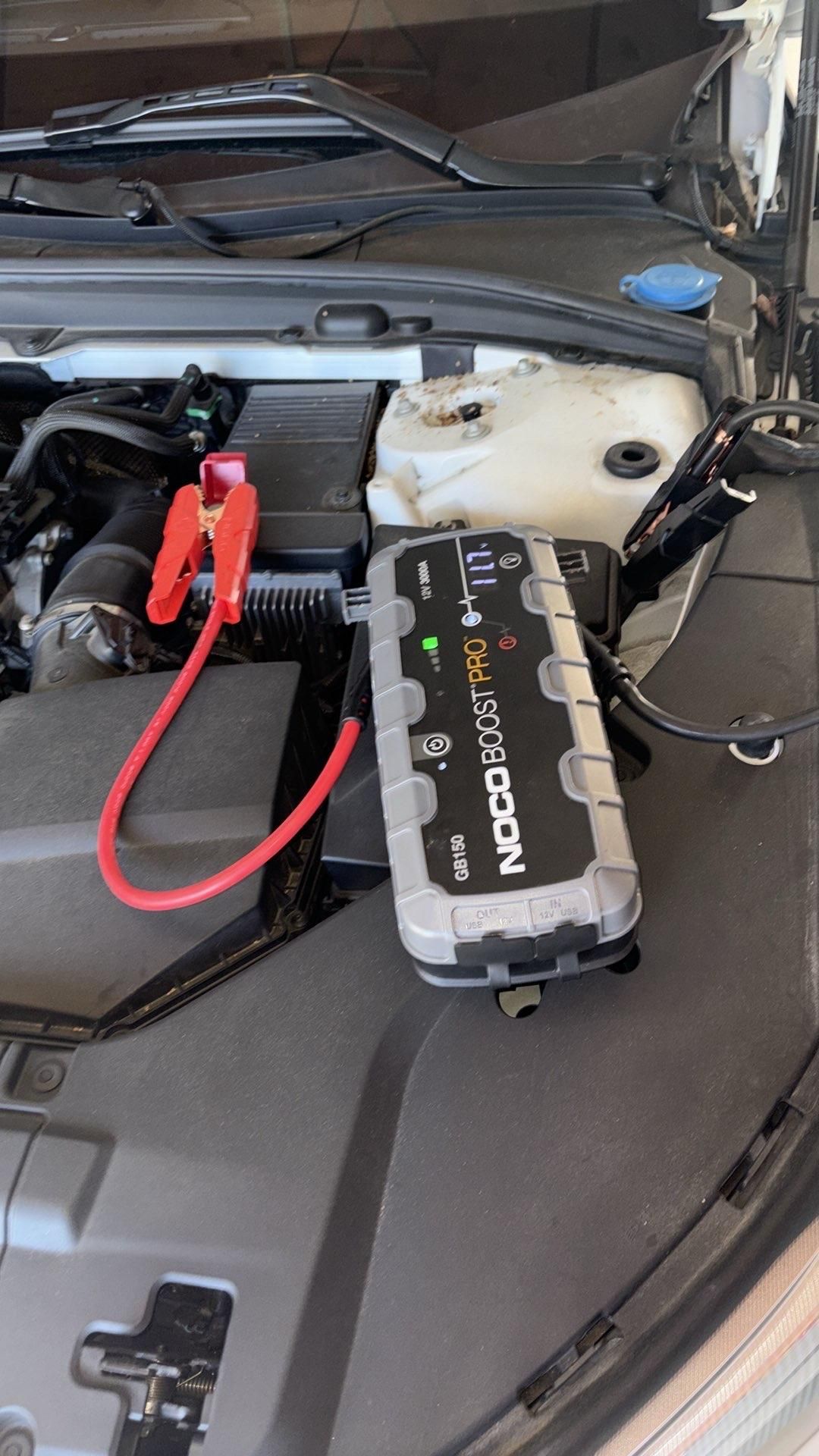 Car engine bay with jumper cables connected to the battery, red and black cables visible. Car engine bay with jumper cables connected to the battery, red and black cables visible.