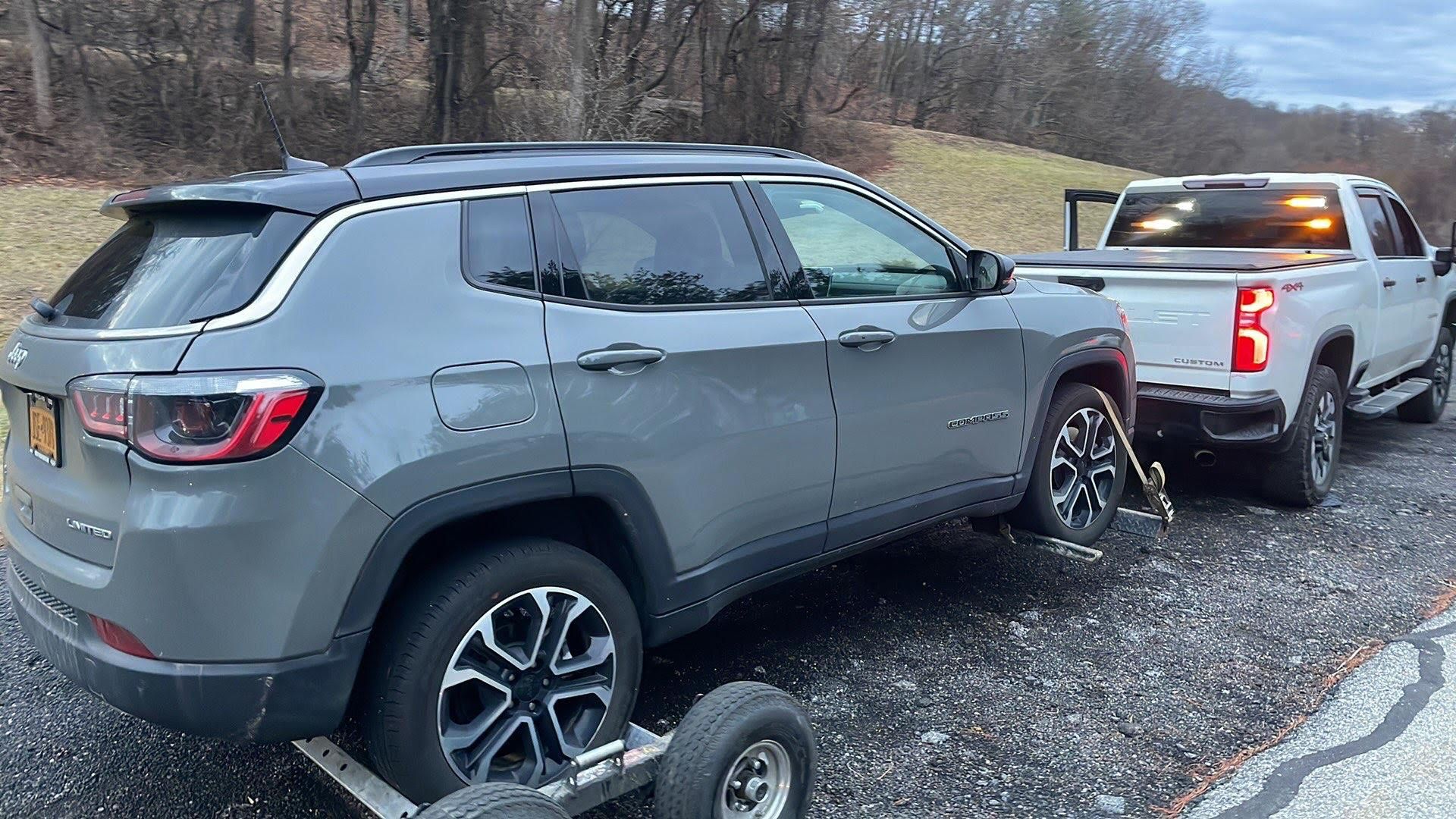 Mechanic changing a tire on a white car, using a lug wrench.