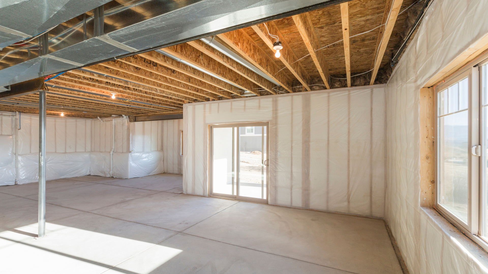 An empty basement with a sliding glass door and windows.