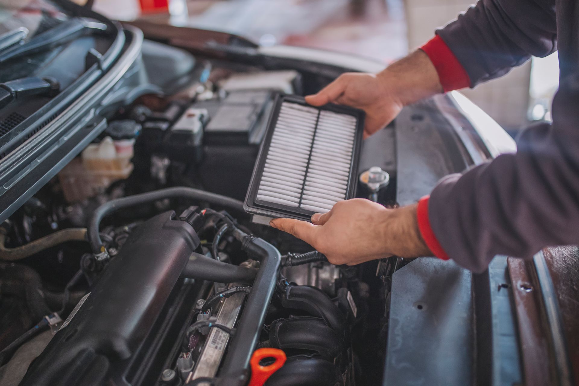 Person replacing an air filter in a car engine.