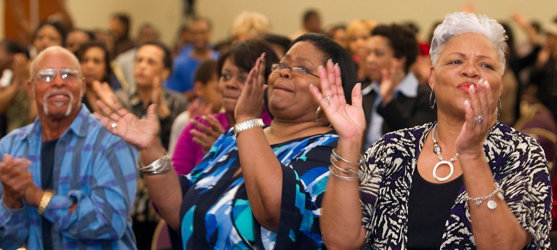 Four people in white clothing singing with sunlight streaming down.