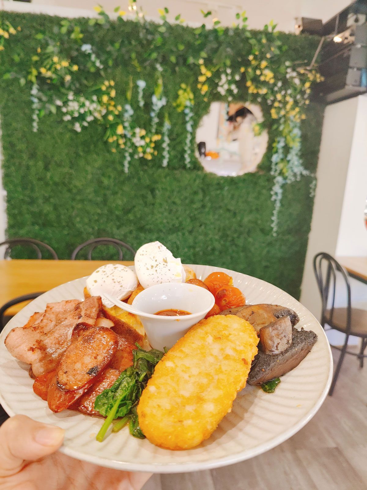 A person is holding a plate of food in front of a green wall.