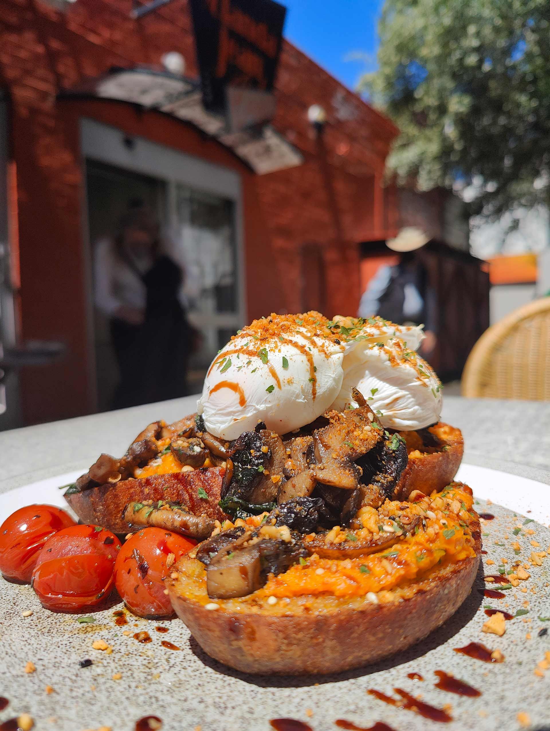 a close up of a plate of food with tomatoes and poached eggs on a table .