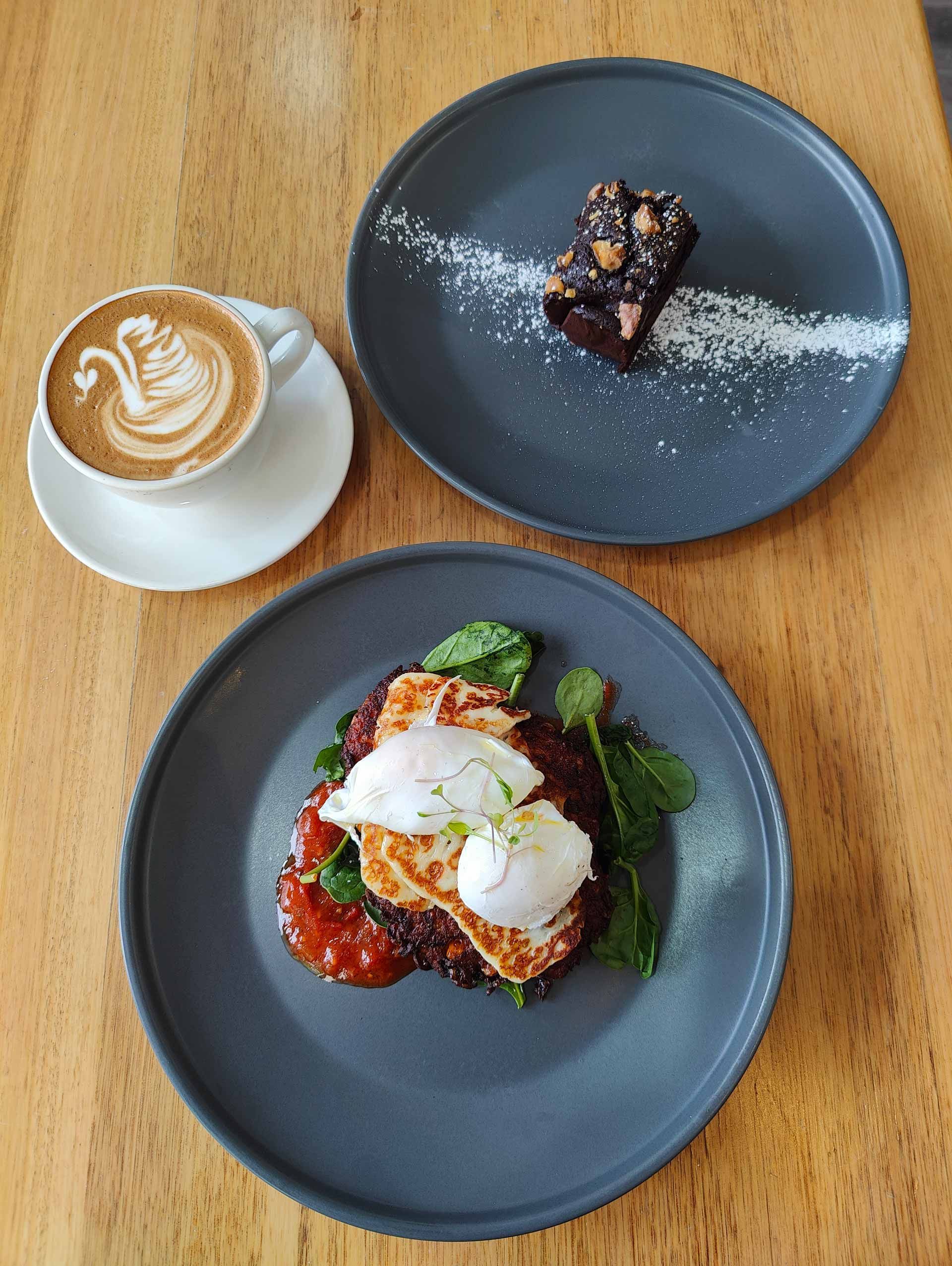 a wooden table topped with plates of food and a cup of coffee .
