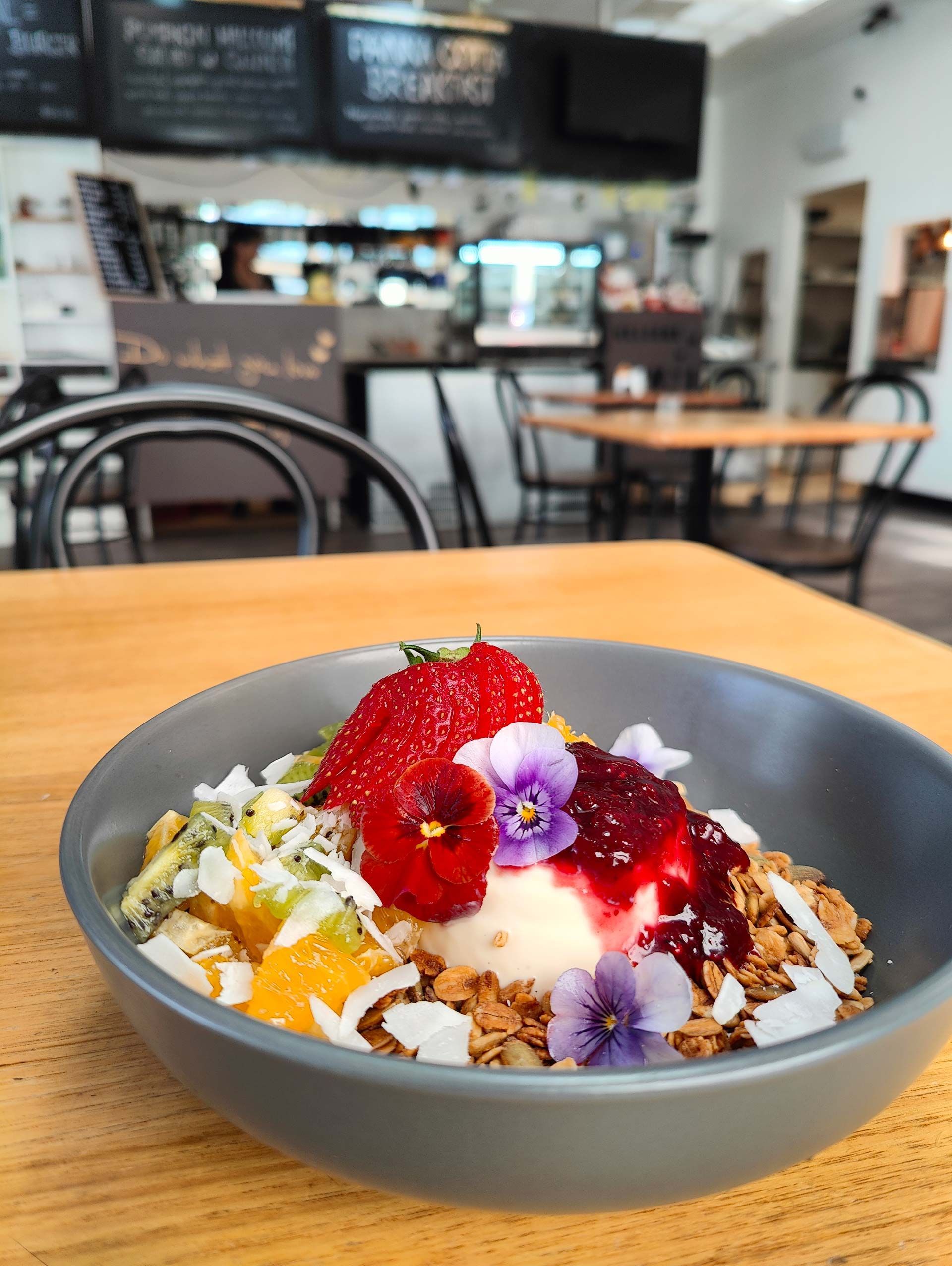 a bowl of food with ice cream and fruit on a table in a restaurant .